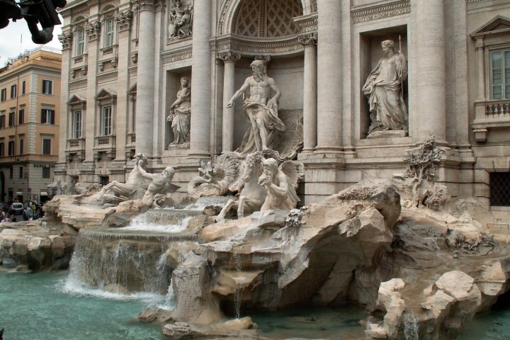 a large stone statue in front of Trevi Fountain