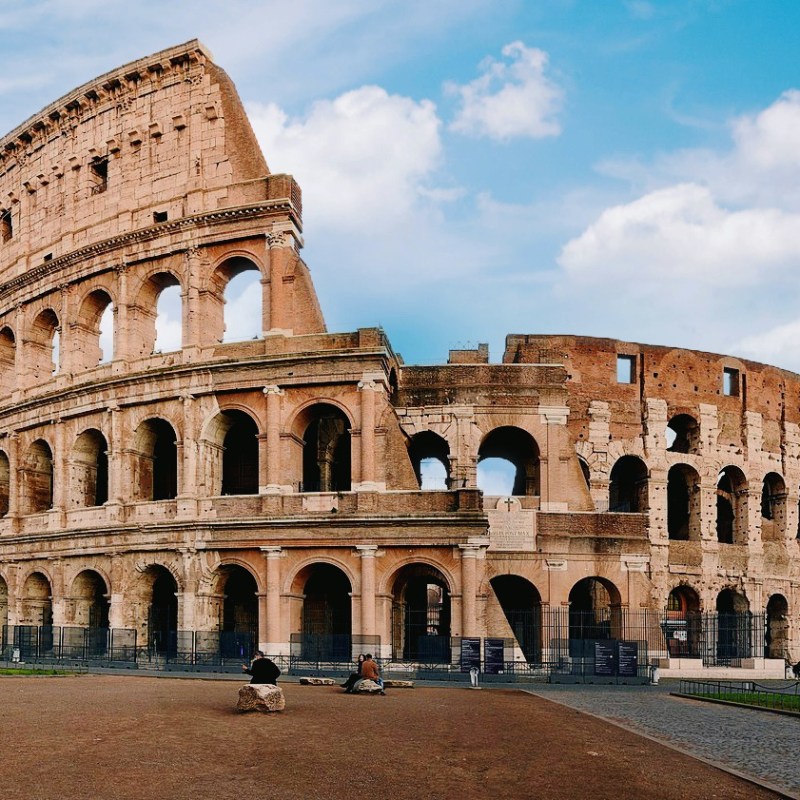 a large stone building with Colosseum in the background