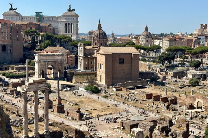 a pile of dirt in front of a castle with Roman Forum in the background