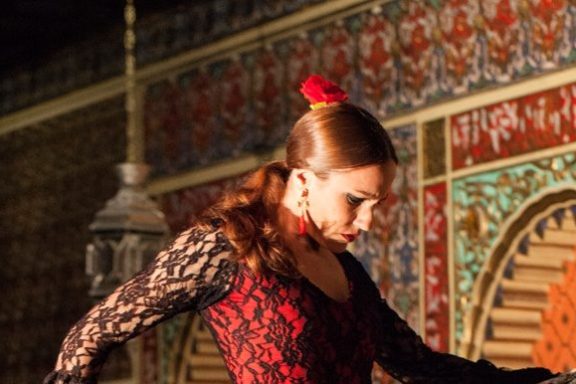 A flamenco dancer on stage, wearing a traditional dress