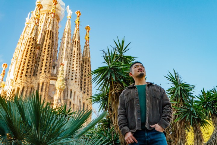 a man standing in front of a palm tree with Sagrada Família in the background