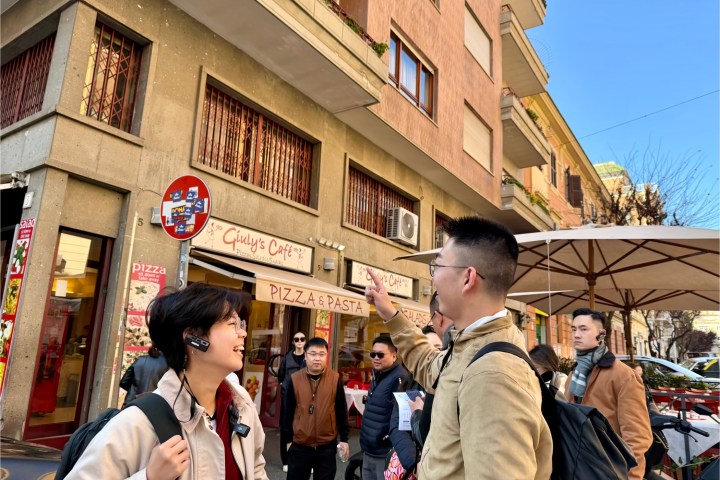 Group of people on a street near a cafe, with one person pointing.
