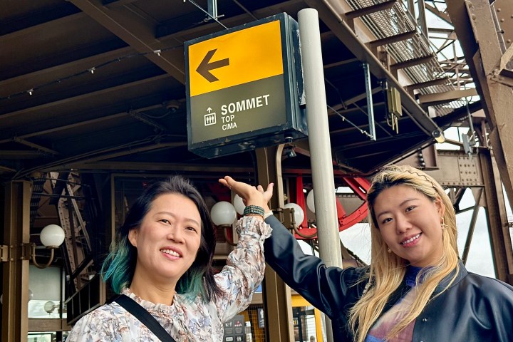 Two people smiling and pointing at a 'Sommet Top Cima' sign.