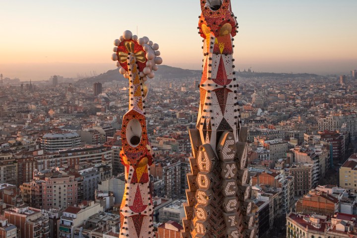 Aerial view of colorful spires of a cathedral with cityscape in background at sunset.