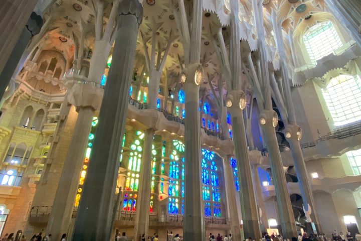Interior of a cathedral with tall columns and colorful stained glass windows.