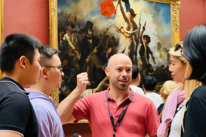 A group of people discussing in front of a large painting in a museum.