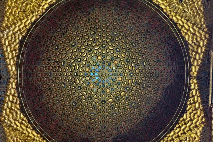 Ornate golden dome ceiling with intricate geometric patterns and arches.