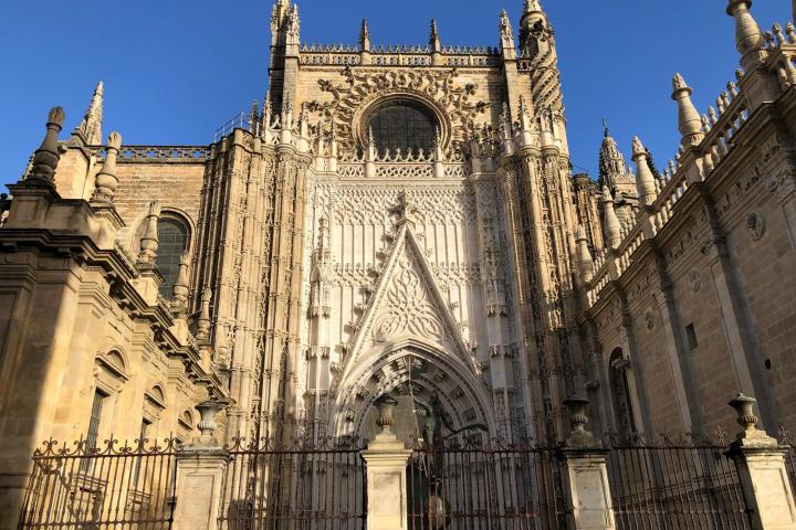 Ornate Gothic cathedral facade with spires and an arched entrance under a clear blue sky.