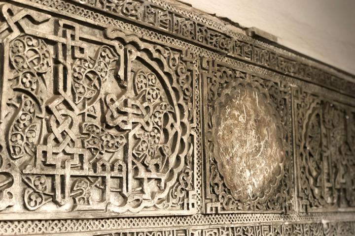 Intricate stone wall panel with ornate geometric and floral patterns.