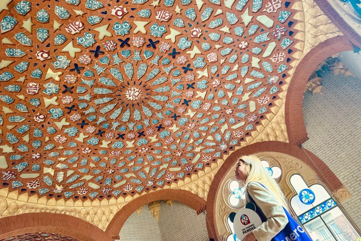 Woman in front of ornate, colorful mosaic-patterned ceiling with rings and star shapes. Taken during the sant pau art nouveau site tour.