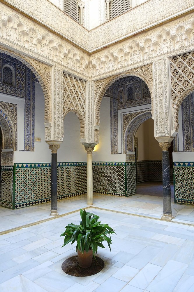 Intricate arched courtyard with patterned tiles and a potted plant center, showcasing ornamental architecture.