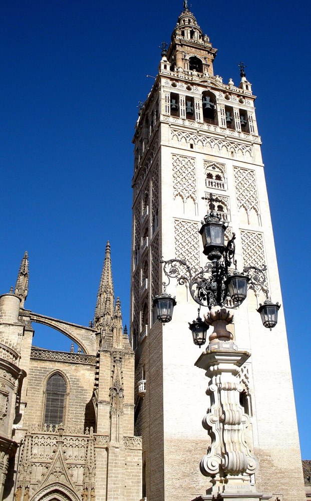 Historic tall bell tower with ornate details against a clear blue sky.