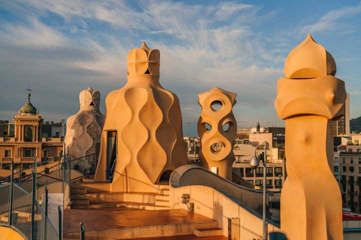Architectural chimneys on a rooftop with cloudy sky background.