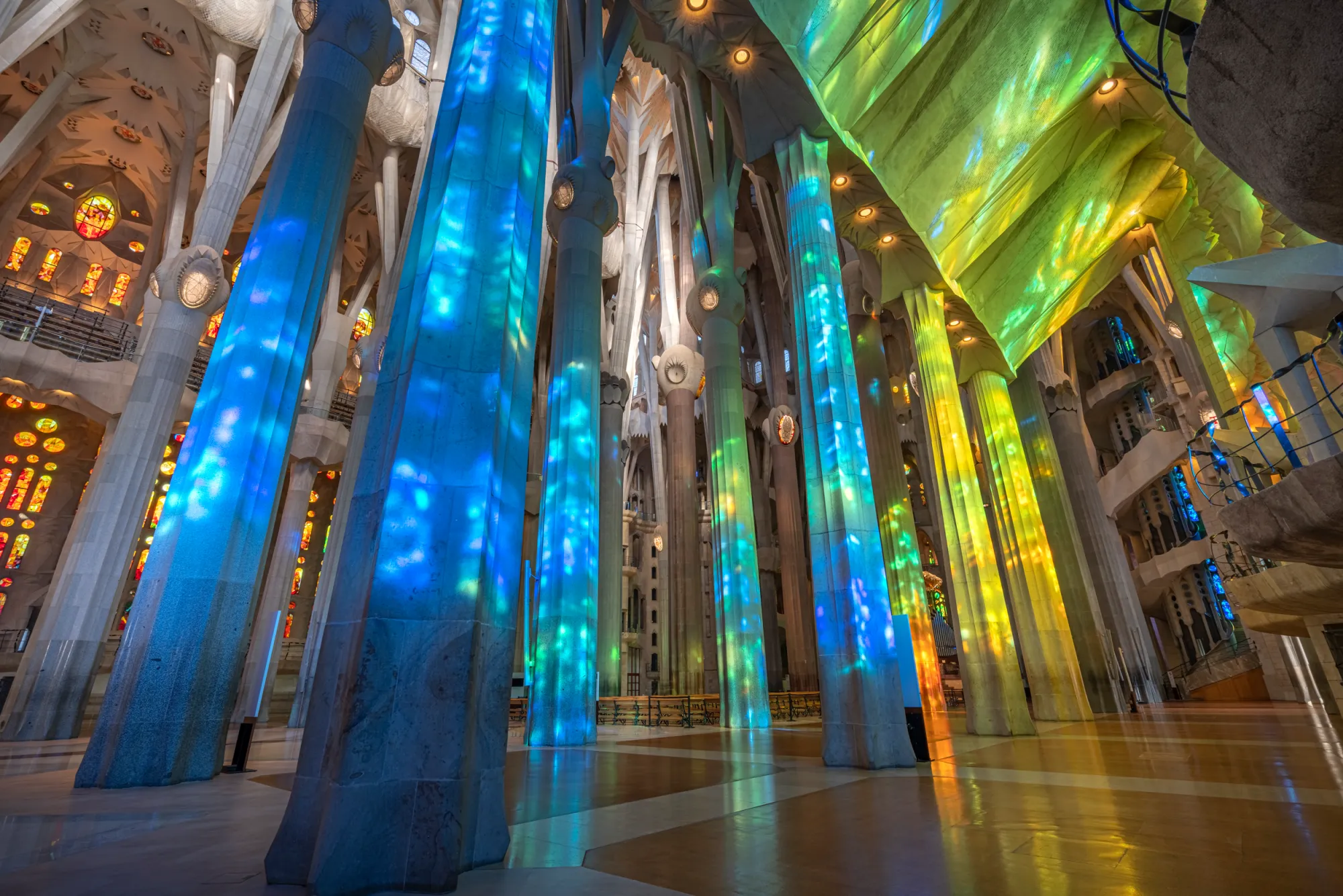 Interior of a cathedral with tall columns and colorful stained glass windows.