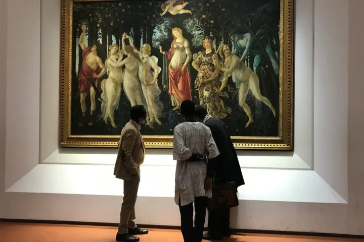 Three people viewing a large, detailed painting in a museum.