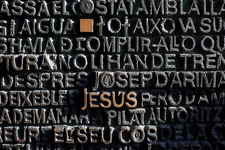 Stone wall with engraved text, featuring the word 'Jesus' in gold.