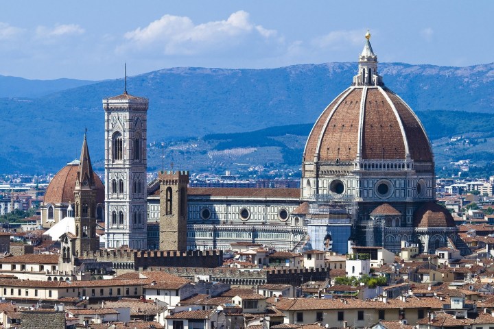 Florence Cathedral with a large dome and bell tower, city and hills in the background.
