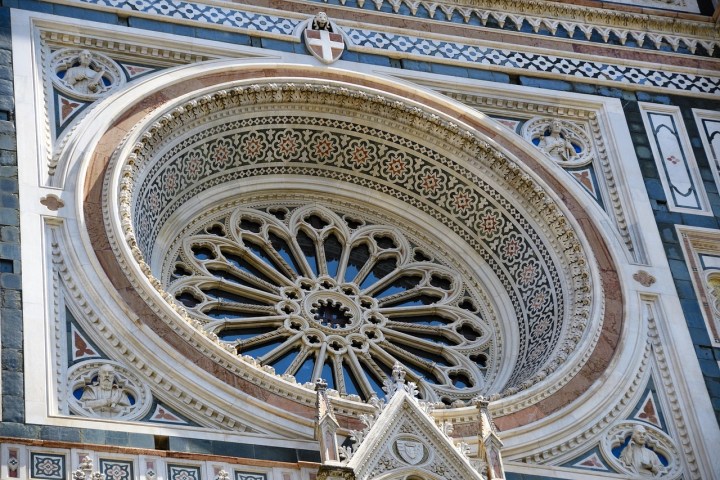 Ornate rose window with Gothic-style details on a cathedral facade.