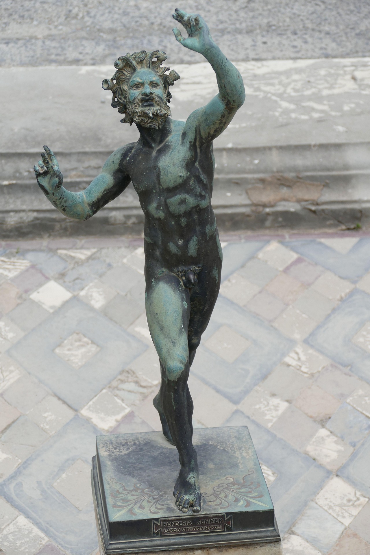 Pompeii Bronze statue of a dynamic, bearded male figure raising both arms on a patterned base.