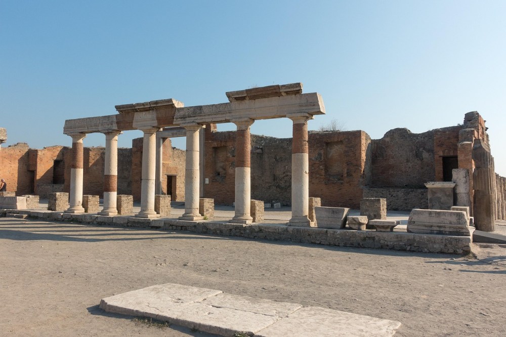 Ruins of ancient columns and walls under a clear blue sky.