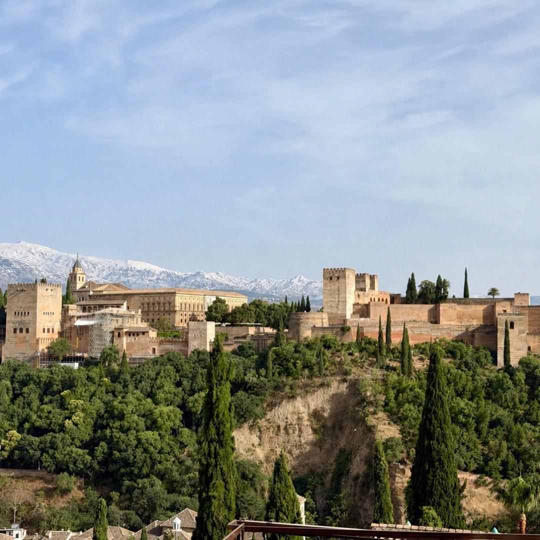 Historic fortress with trees and mountains in the background.