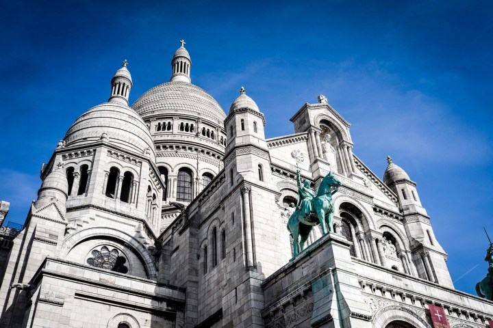 Historic white basilica with domes under clear blue sky.