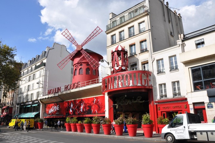 Front view of the Moulin Rouge with red windmill and large red planters.