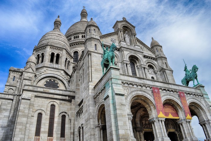 Sacre-Coeur Basilica with blue sky and statue in foreground.