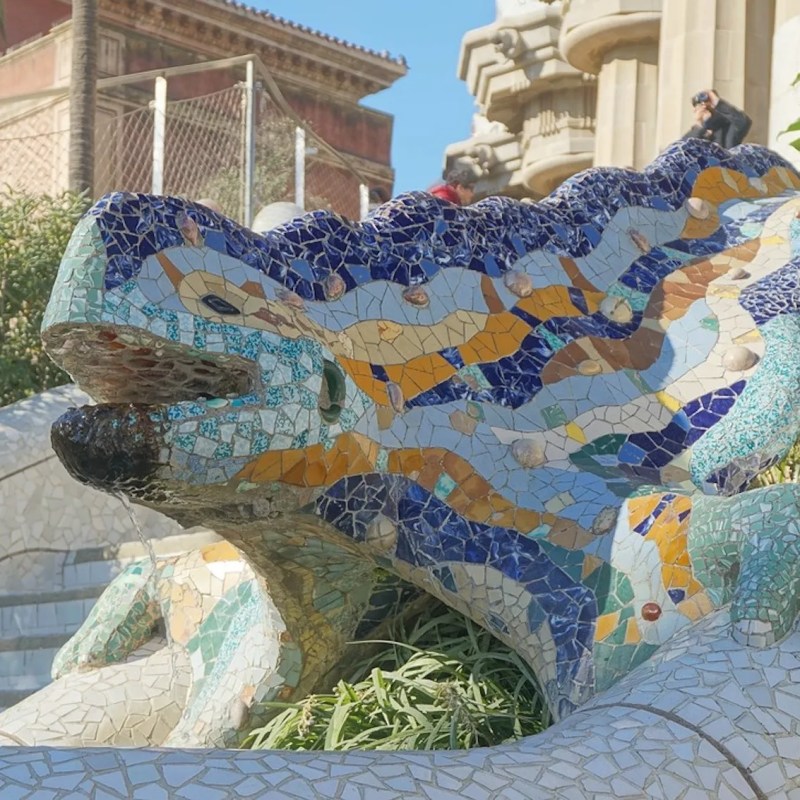 Mosaic lizard sculpture on steps with colorful tiles.