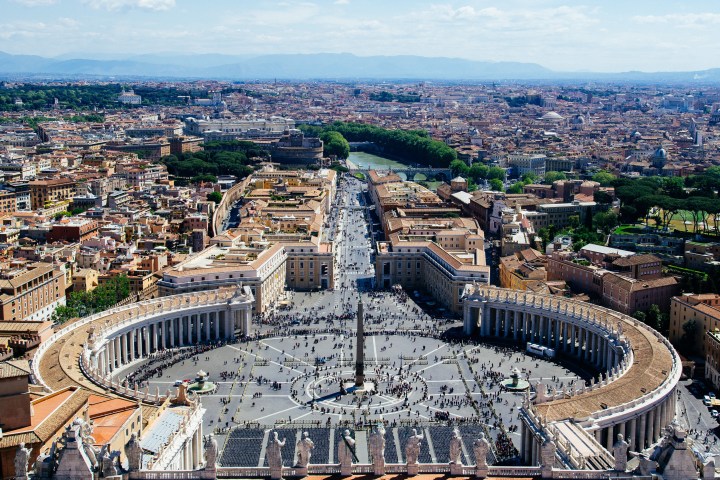 Aerial view of St. Peter's Square in Vatican City with Rome in the background.