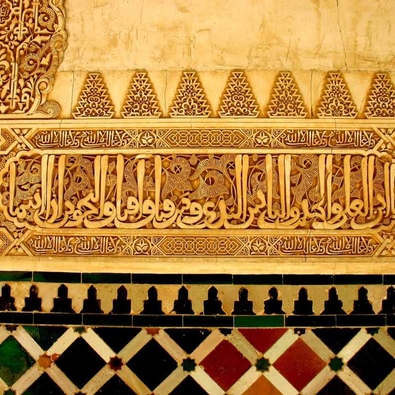 Intricate Arabic calligraphy and tile work on a decorative wall.