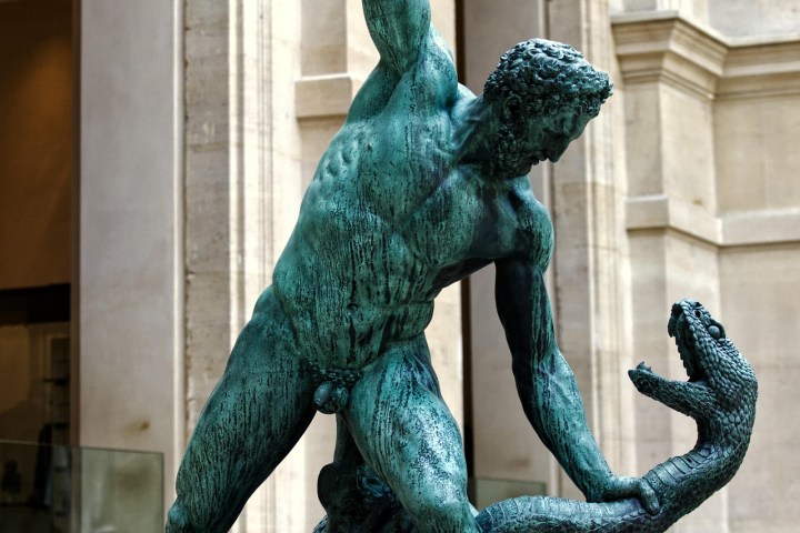A bronze statue of the muscular mythological hero Hercules wrestling a large serpent, created by François-Joseph Bosio and displayed in the Louvre Museum.